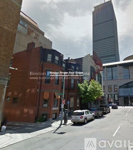 A street view of a city with a tall building in the background.