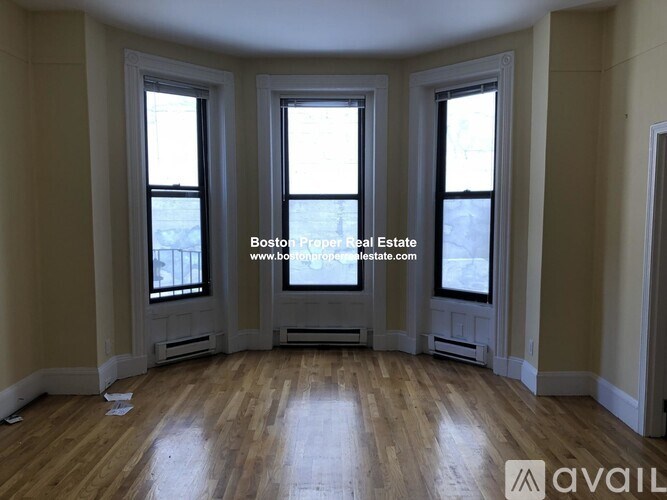A room with wooden floors and three windows.