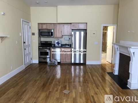 A kitchen with wooden floors and a white fireplace.