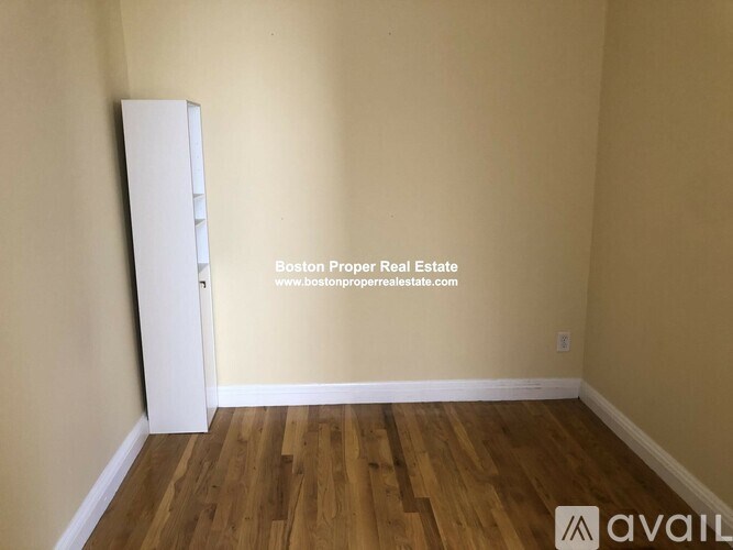 A room with wooden flooring and a white cabinet.