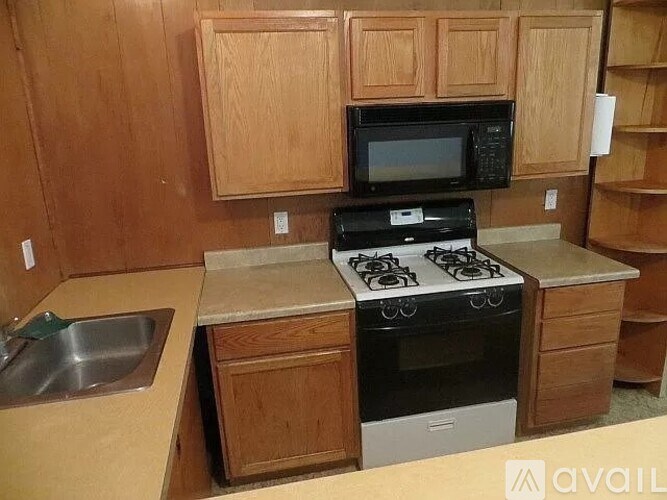 A kitchen with a stove, sink, and microwave.