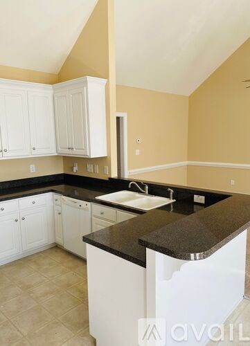 A kitchen with white cabinets and a black countertop.