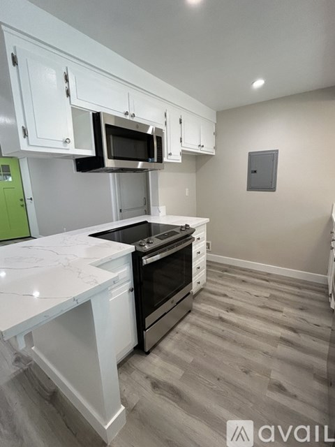 A kitchen with white cabinets and a marble countertop.