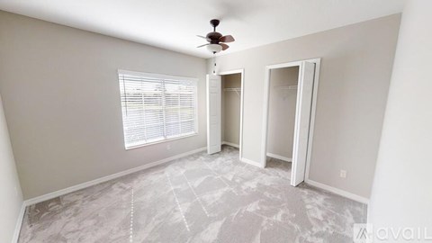 A room with a ceiling fan and a window with blinds.