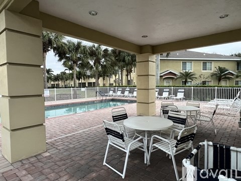 A patio with a table and chairs overlooking a pool.