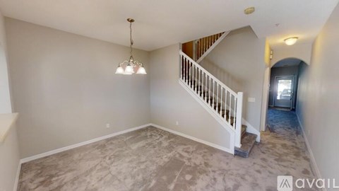 A spacious room with a staircase and a chandelier.