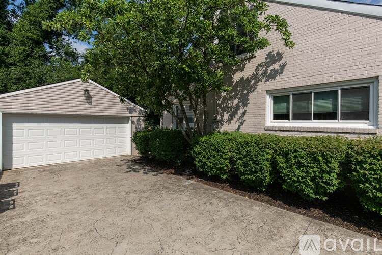 A house with a garage and a tree in front.