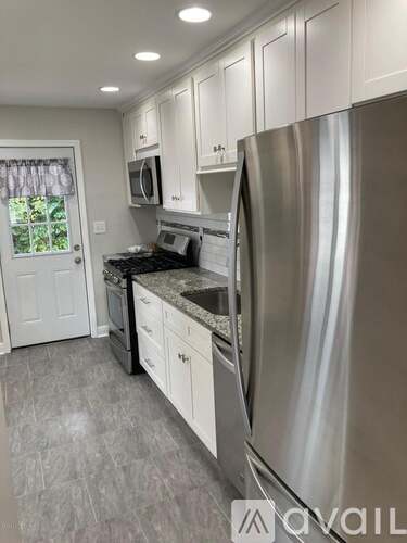 A kitchen with a stainless steel refrigerator and white cabinets.