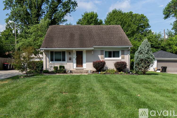 A house with a brown roof and a front yard with a tree.