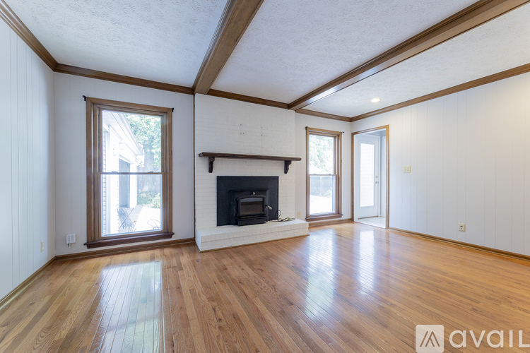 A spacious room with wooden floors and a fireplace.