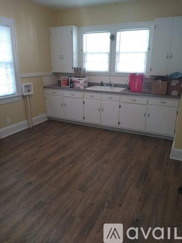 A kitchen with white cabinets and wooden floors.