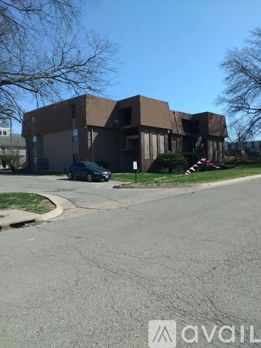 A black car is parked in front of a brown building.