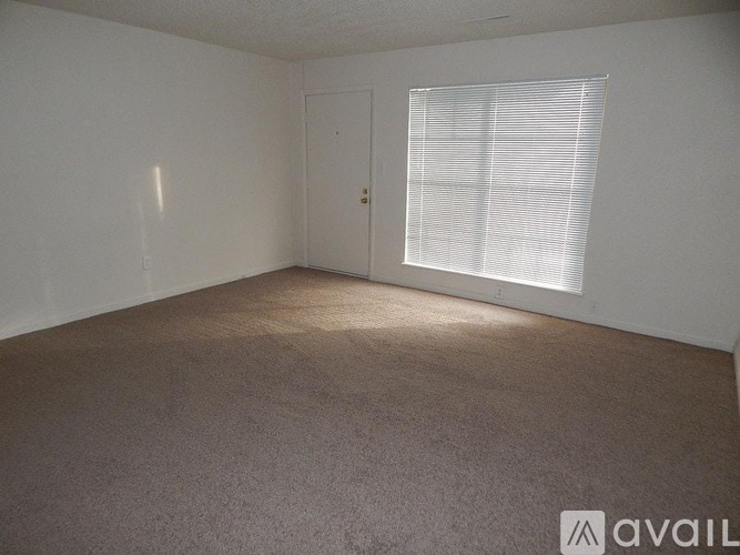 A room with a carpeted floor, a door, and a window with blinds.