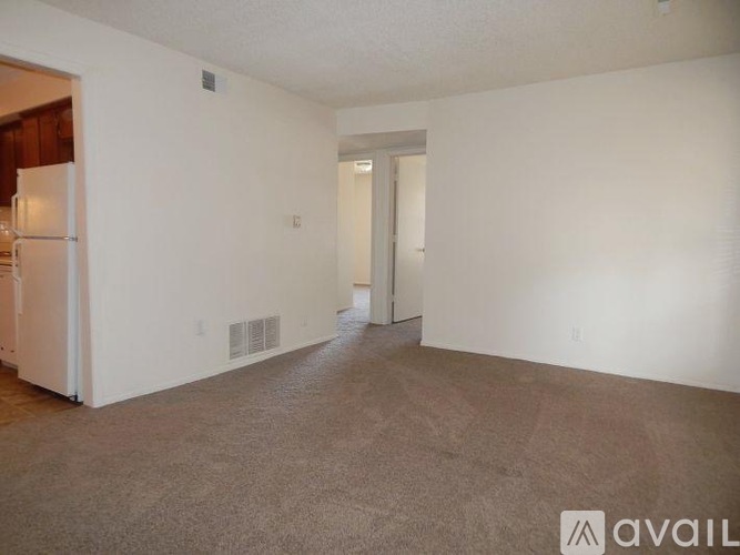 A room with carpeted floor and white walls with a doorway leading to another room.