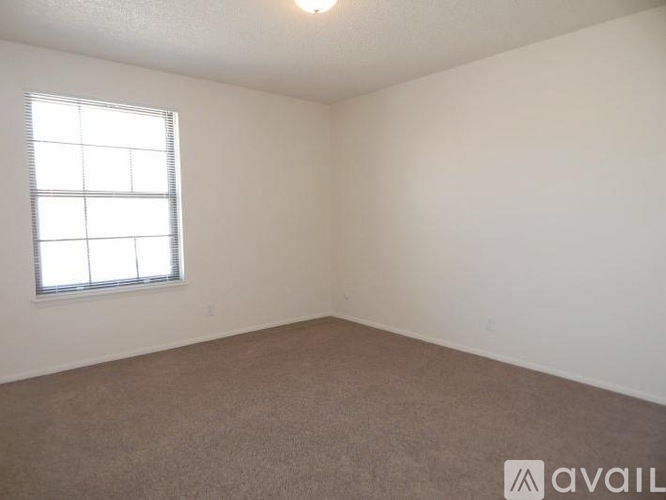 A room with a carpeted floor and a window with blinds.