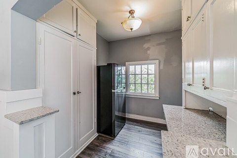 A kitchen with white cabinets and a black refrigerator.