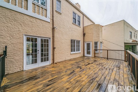 A wooden deck is attached to a tan building.