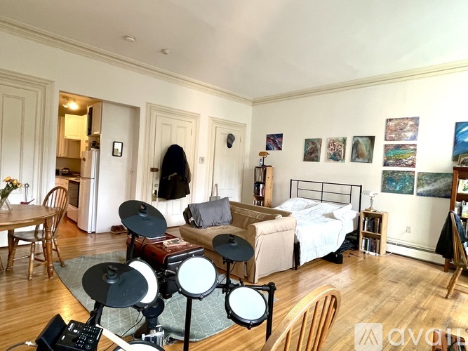 A room with a bed, a couch, a chair, and a table with a laptop on it.