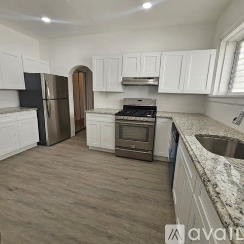 A kitchen with white cabinets and a marble countertop.