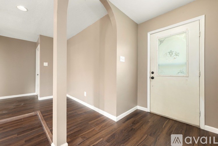 A spacious living room with wood flooring and arched doorways.