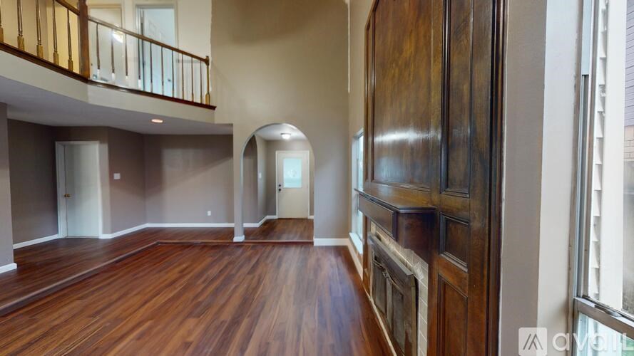 A room with wooden floors and a balcony with railings.