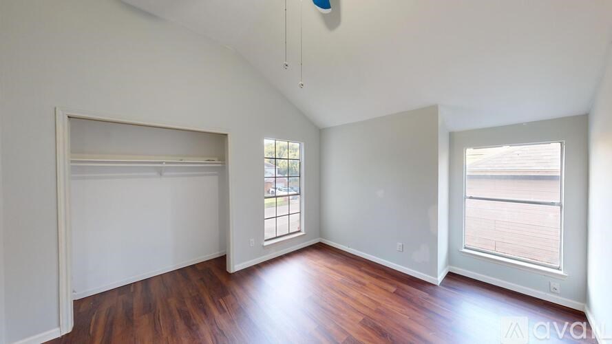 A room with wooden floors and white walls, with a window on the right side.