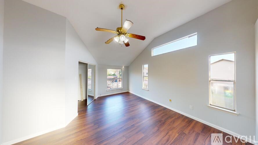 A spacious room with a ceiling fan and wooden flooring.