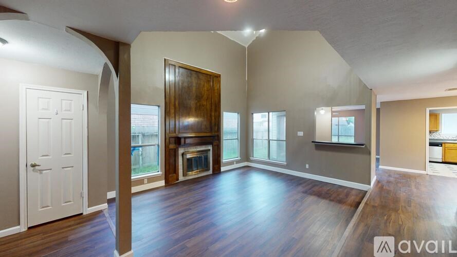 A spacious living room with wood flooring and a fireplace.