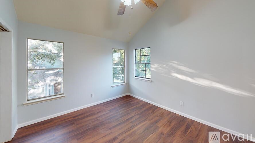 A room with wooden floors and two windows.