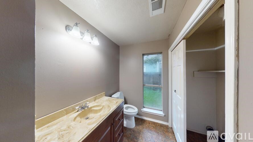 A bathroom with a sink, toilet, and window.