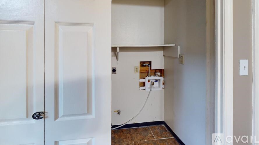 A white door is open to a hallway with a shelf and boxes on it.