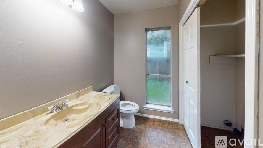 A bathroom with a sink, toilet, and a window.