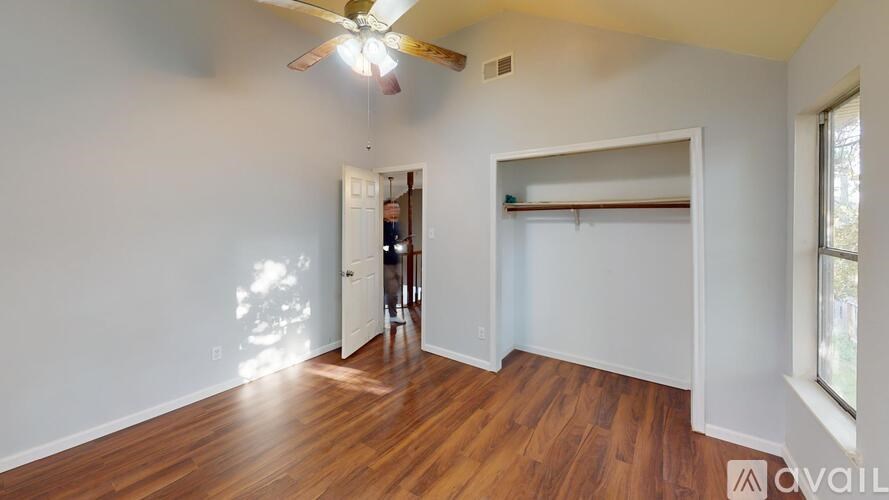 A room with a ceiling fan and wooden floors.