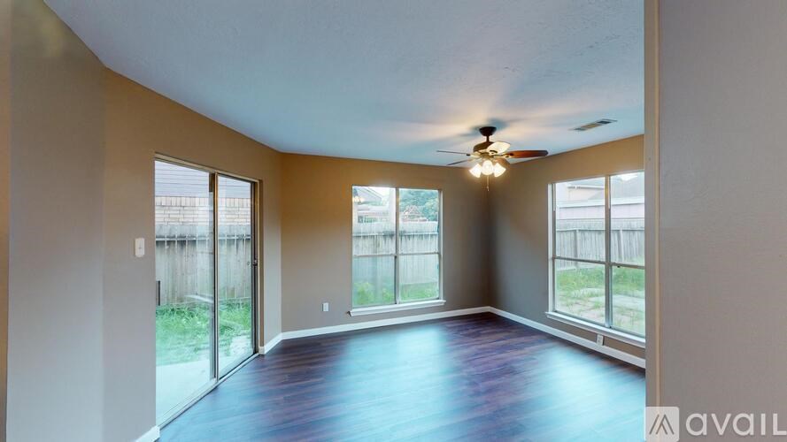 A room with a ceiling fan and sliding glass doors.