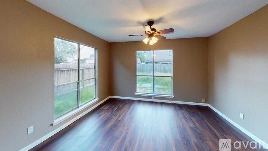 A room with a ceiling fan and wooden flooring.
