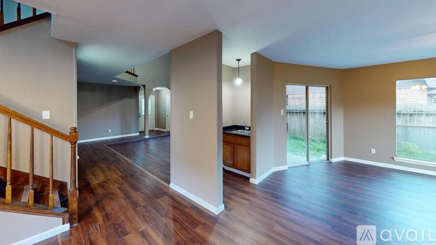 A spacious living room with hardwood floors and a staircase with wooden railings.
