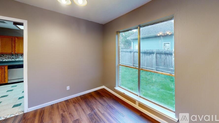 A room with a large window and wooden flooring.