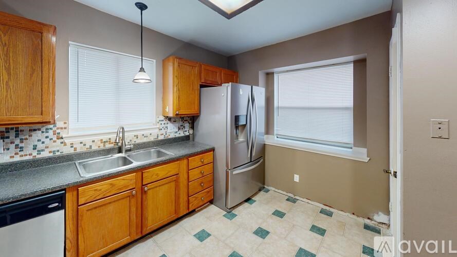 A kitchen with wooden cabinets and a stainless steel refrigerator.