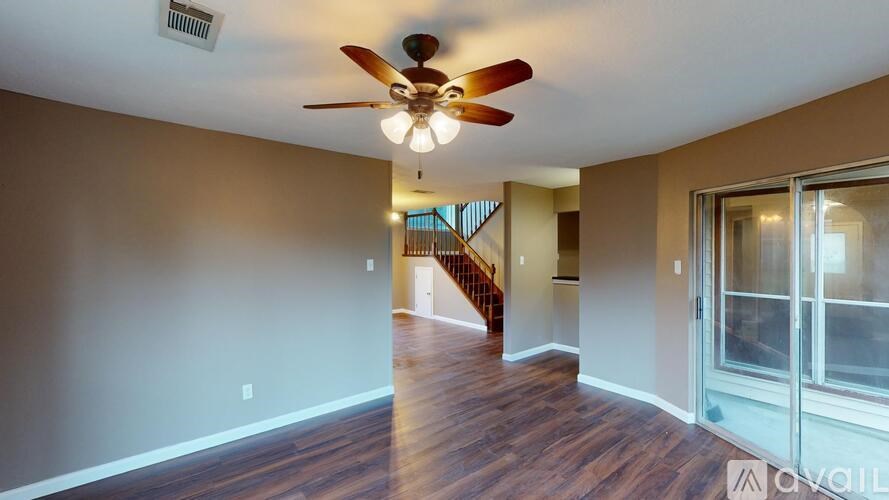 A room with a ceiling fan and wooden flooring.