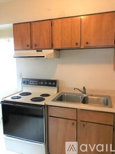 A kitchen with wooden cabinets and a white stove top oven.