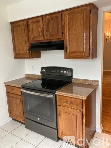 A black stove top oven with a digital display is installed in a kitchen with wooden cabinets.