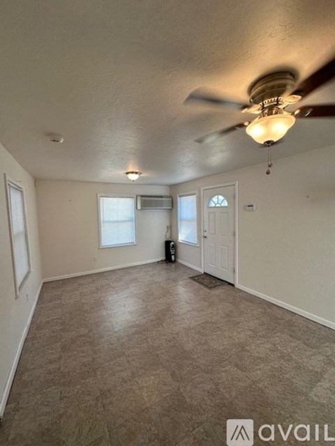 A room with a ceiling fan and a door.