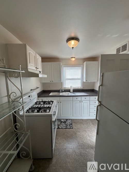 A kitchen with white cabinets and a white fridge.