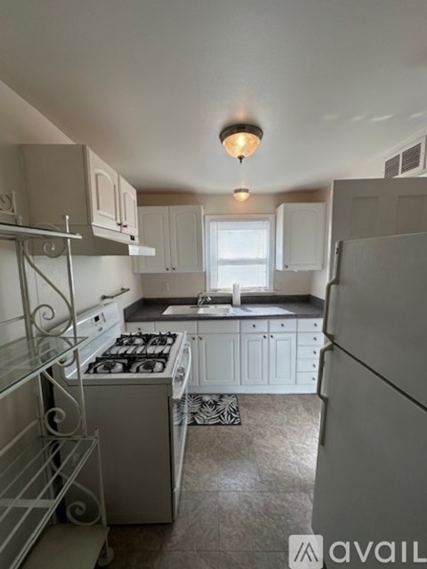 A kitchen with white cabinets and a white fridge.