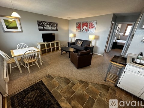 A living room with a white chair set and a brown couch.
