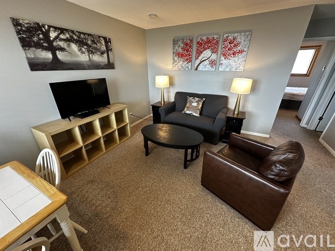 A living room with a brown leather couch, a wooden table, and a television.