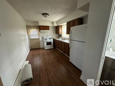 A kitchen with white appliances and wooden floors.