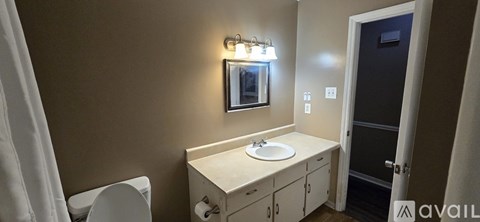 A bathroom with a toilet, sink, and mirror.