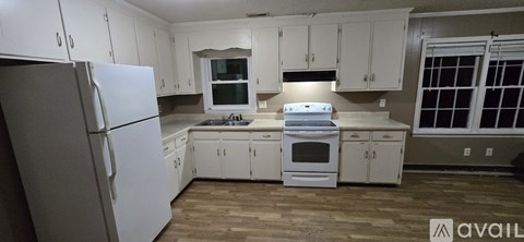 A kitchen with white cabinets and appliances is available for rent.