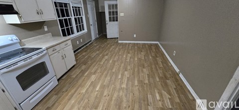 A kitchen with white cabinets and a wooden floor.